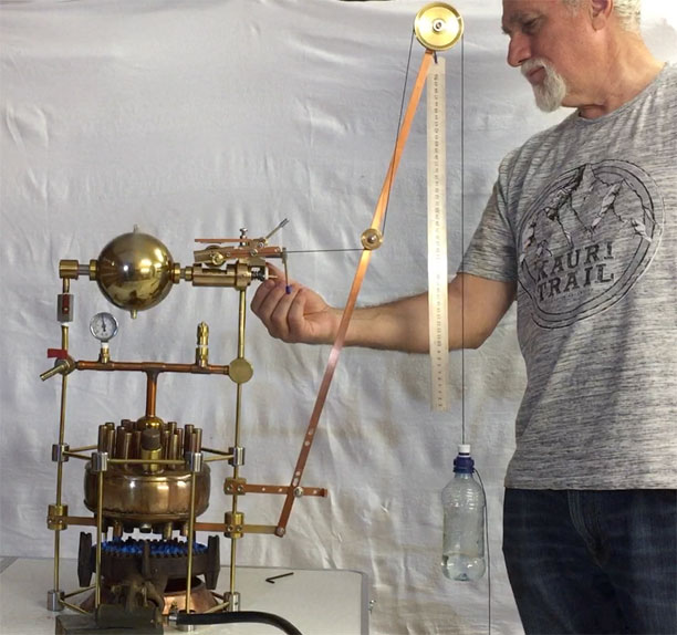 Photo of the crane lifting a bottle of water powered by the Hero engine as the operator adjusts the pivots. Pressure Gauge reads 8 psi.
                        